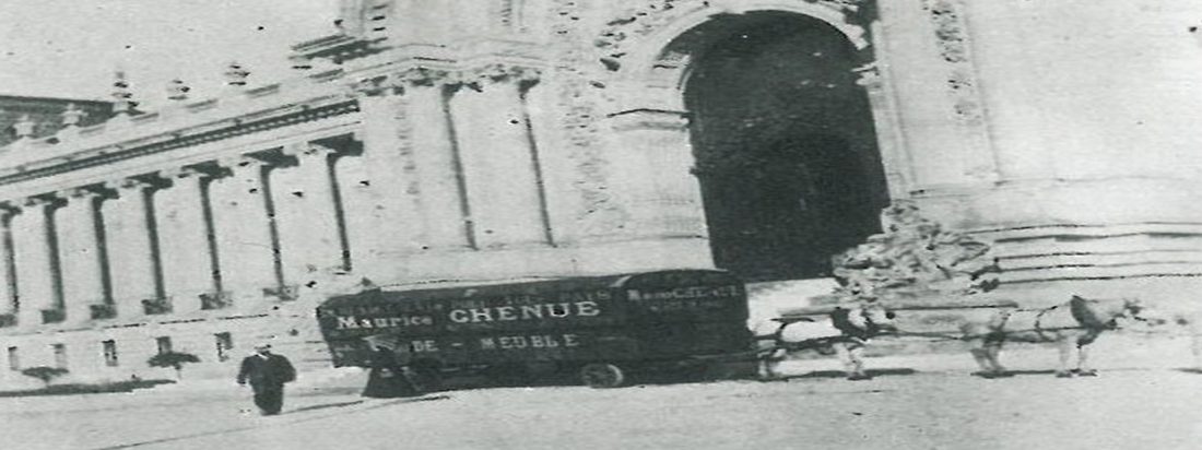 Foto em preto e branco de uma carroça puxada a cavalo com a inscrição Maison Chenue diante de um edifício de colunas